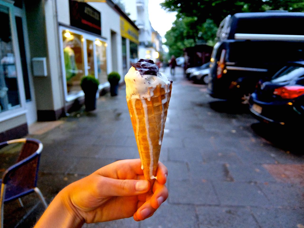 Melting ice cream cone held outside Eisliebe on a warm day