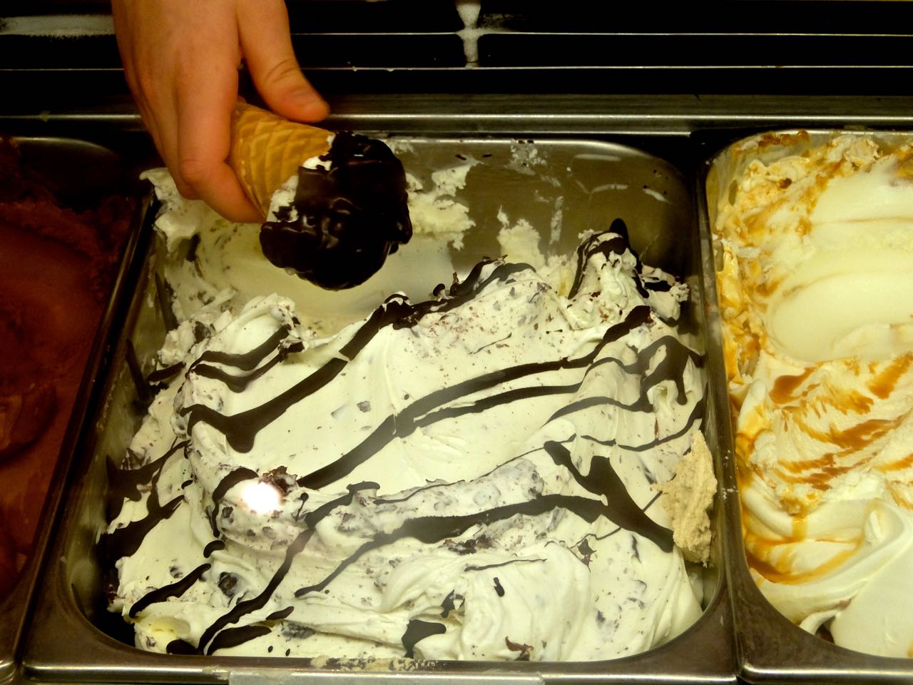 An Eisliebe ice cream cone being dipped into chocolate