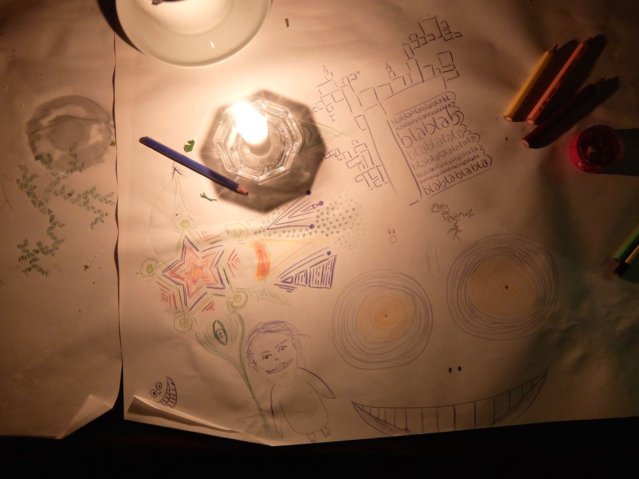 Paper-covered table with drawings, colored pencils, and candlelight at Jimmy Elsass