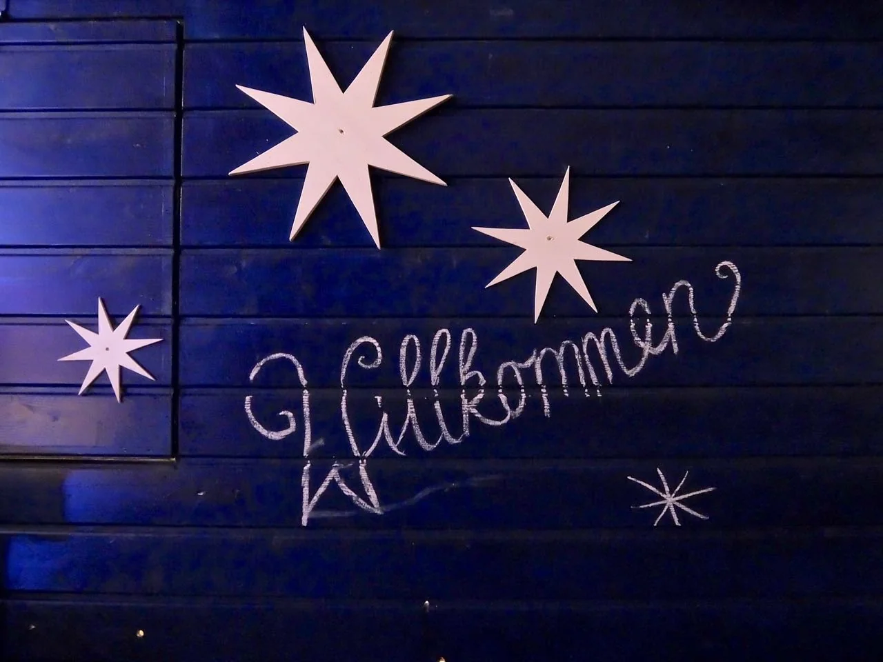 ‘Willkommen’ sign above market-stand huts at the Apostelkirche Christmas market
